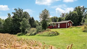 Een rode woning met een witte deur en ramen, omgeven door groen gras en bomen.