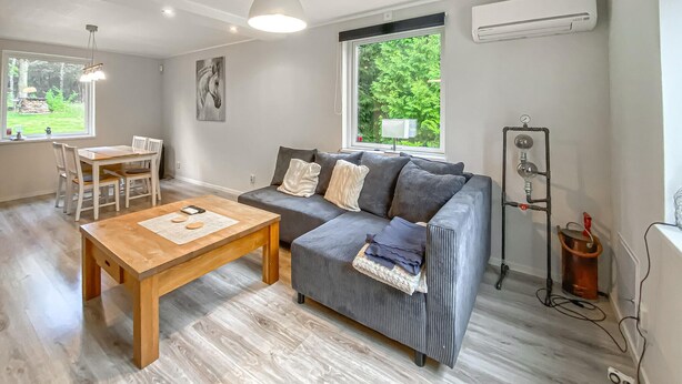 A modern living room with a grey sofa, wooden coffee table, and a dining area with a white table and chairs. - Stunning home in Sjötofta with sauna (Sjötofta)