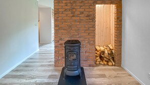 A modern interior with a wood-burning stove, a brick wall, and a wooden door. - Stunning home in Sjötofta with sauna (Sjötofta)