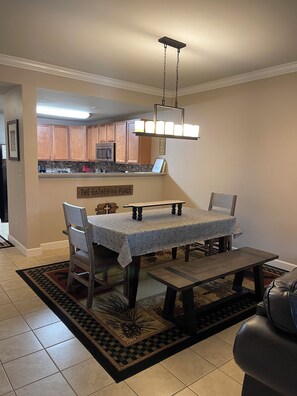 A dining area with a table and chairs, a kitchen in the background, and a sign that reads "THE GATHERING PLACE". - Mountain View Condo 5103 is waiting for you in Pigeon Forge, TN. (Pigeon Forge)