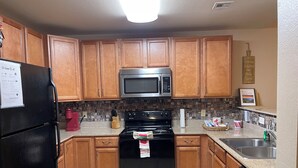 A kitchen with wooden cabinets, a black refrigerator, a stainless steel microwave, a black stove, and a dishwasher.