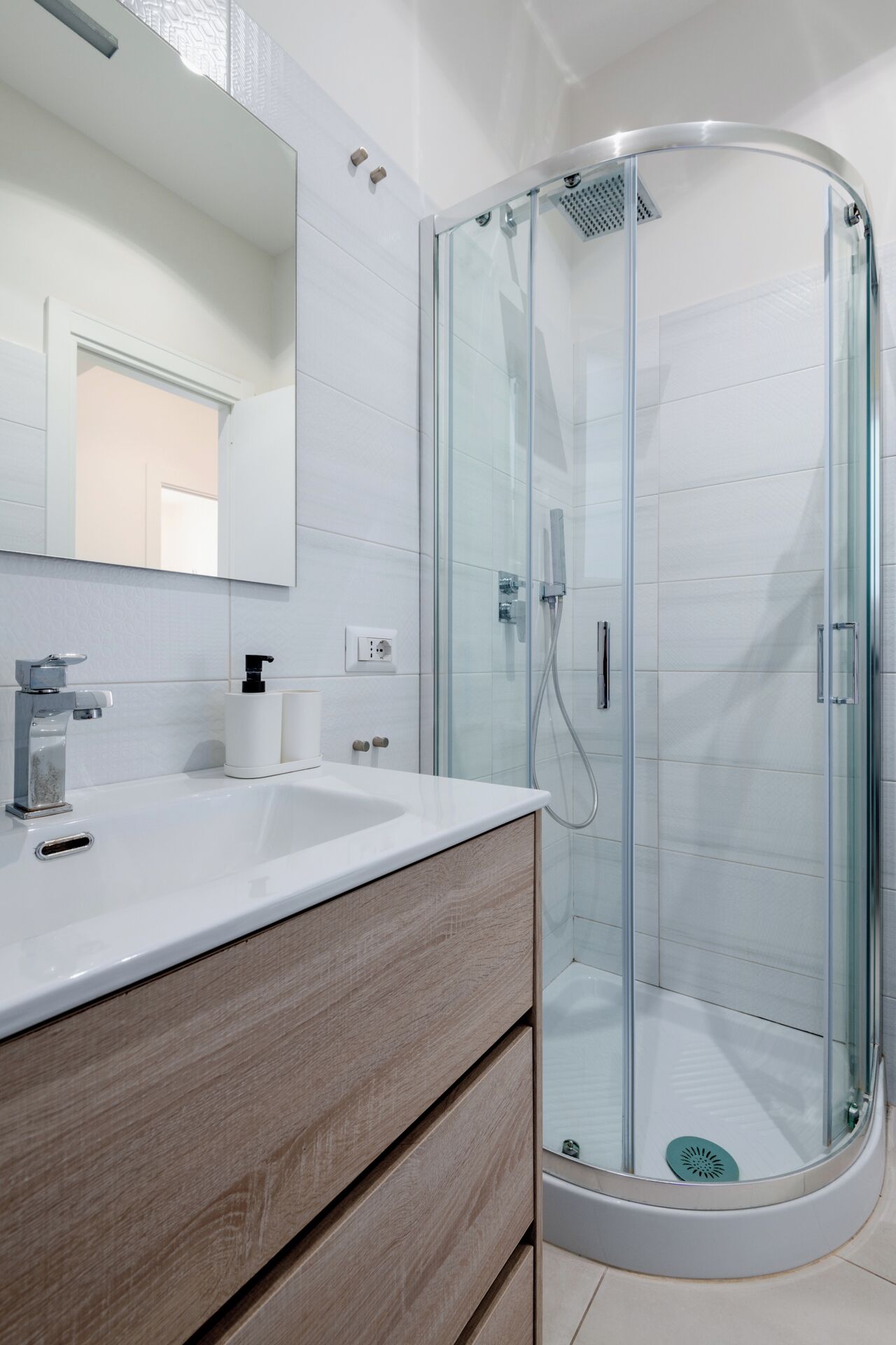 Une salle de bain moderne avec une douche à parois de verre, un lavabo blanc et un meuble-lavabo en bois.