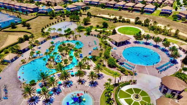 An aerial view of a resort with multiple swimming pools, palm trees, and resort buildings.