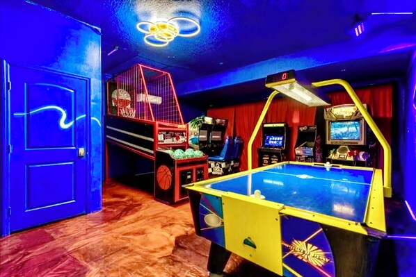 Una sala con mesa de billar, juegos de arcade y aro de baloncesto.