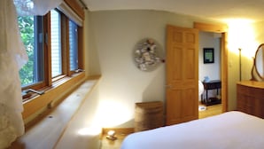 Ein Schlafzimmer mit einem großen Bett, einer Holztür, einem Spiegel und einem Fenster mit Jalousien.