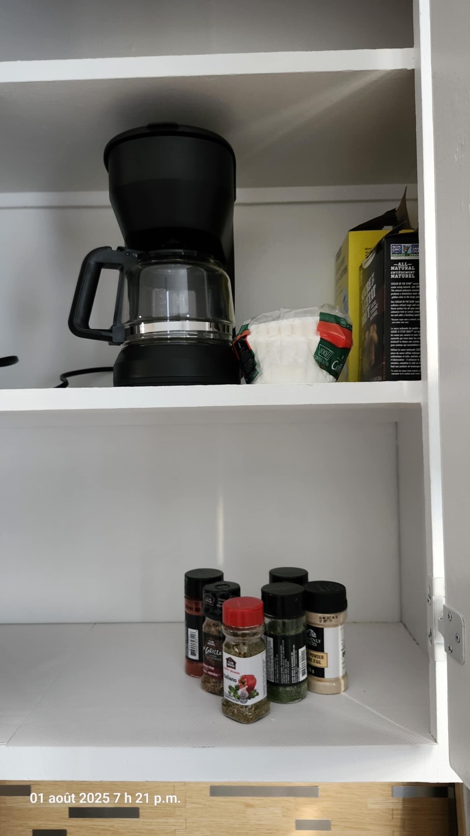 En køkkenhylde med en kaffemaskine, en kaffepose og flere krydderiglas.