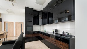 Een moderne keuken met zwarte kastjes, een zwart aanrecht en een zwarte bank.