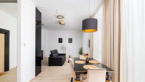 Een moderne eethoek met een zwarte tafel, beige stoelen en een zwarte hanglamp.