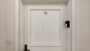 A white door with the number 16, a doorbell, and a door handle. - Kilińskiego Comfy Blue Studio (Łódź)