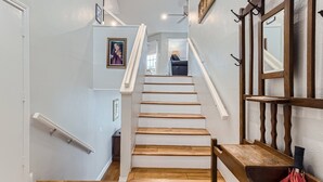 A staircase with wooden steps and a handrail, leading to a room with a chair and a lamp.