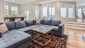 A spacious living room with a large sectional sofa, a glass-top coffee table, and a patterned rug.