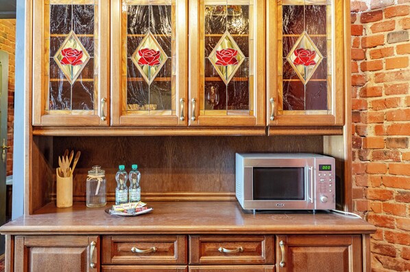 A kitchen with wooden cabinets, a microwave, and a countertop with utensils and condiments.
