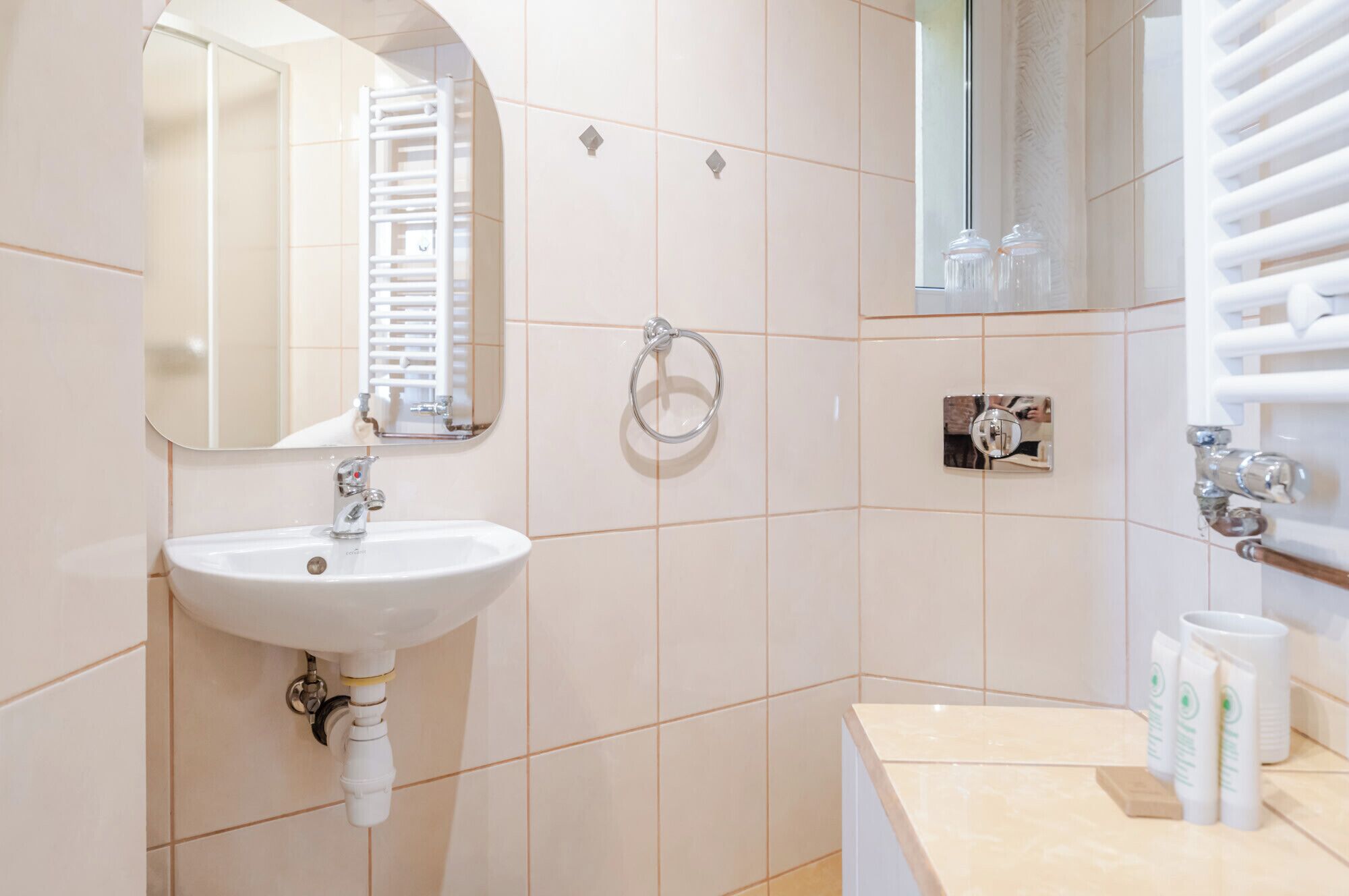 A bathroom with a white sink, a mirror, a towel rack, and a towel dispenser.