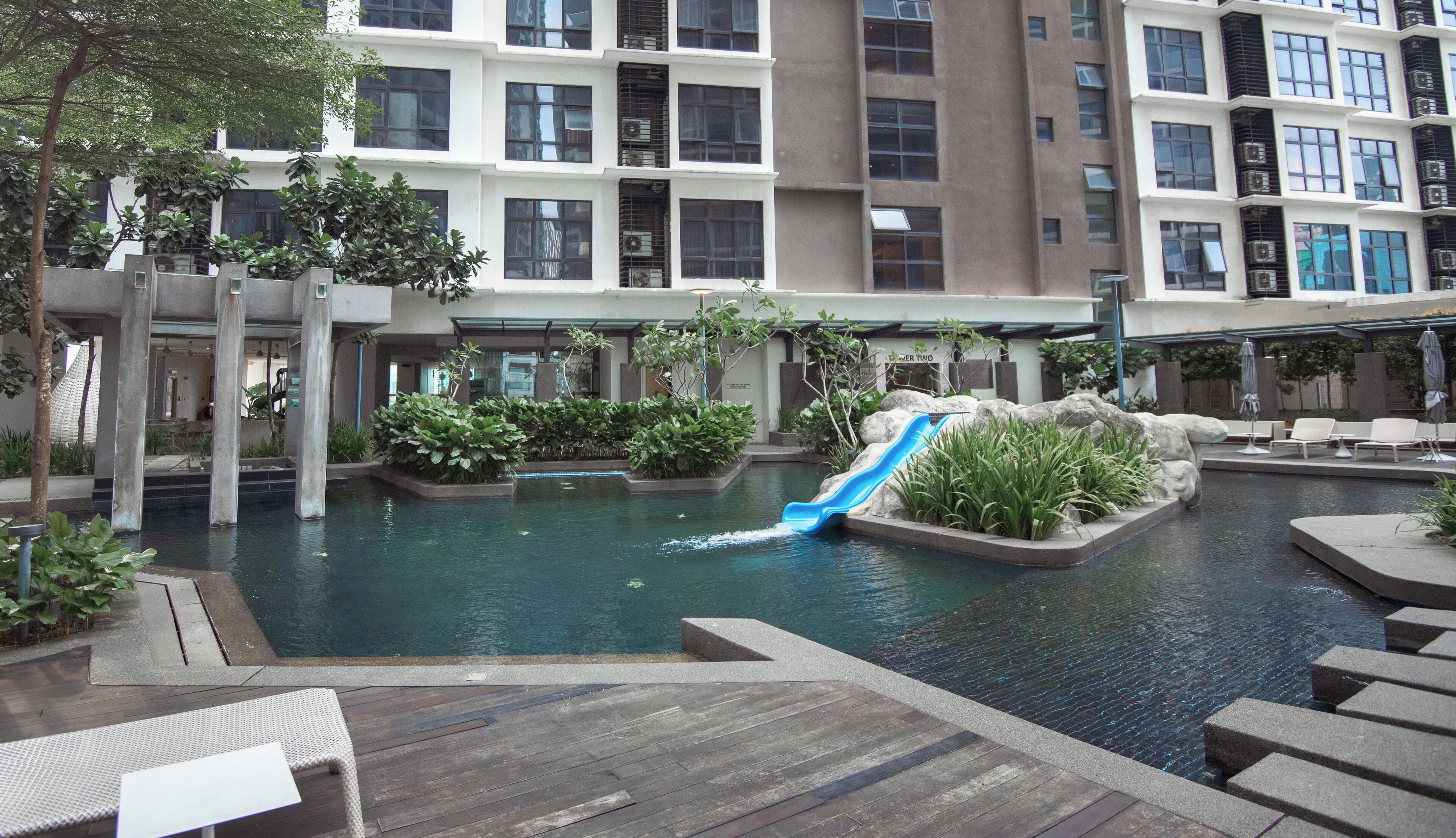 A pool area with a water slide, lounge chairs, and a view of the building's exterior.