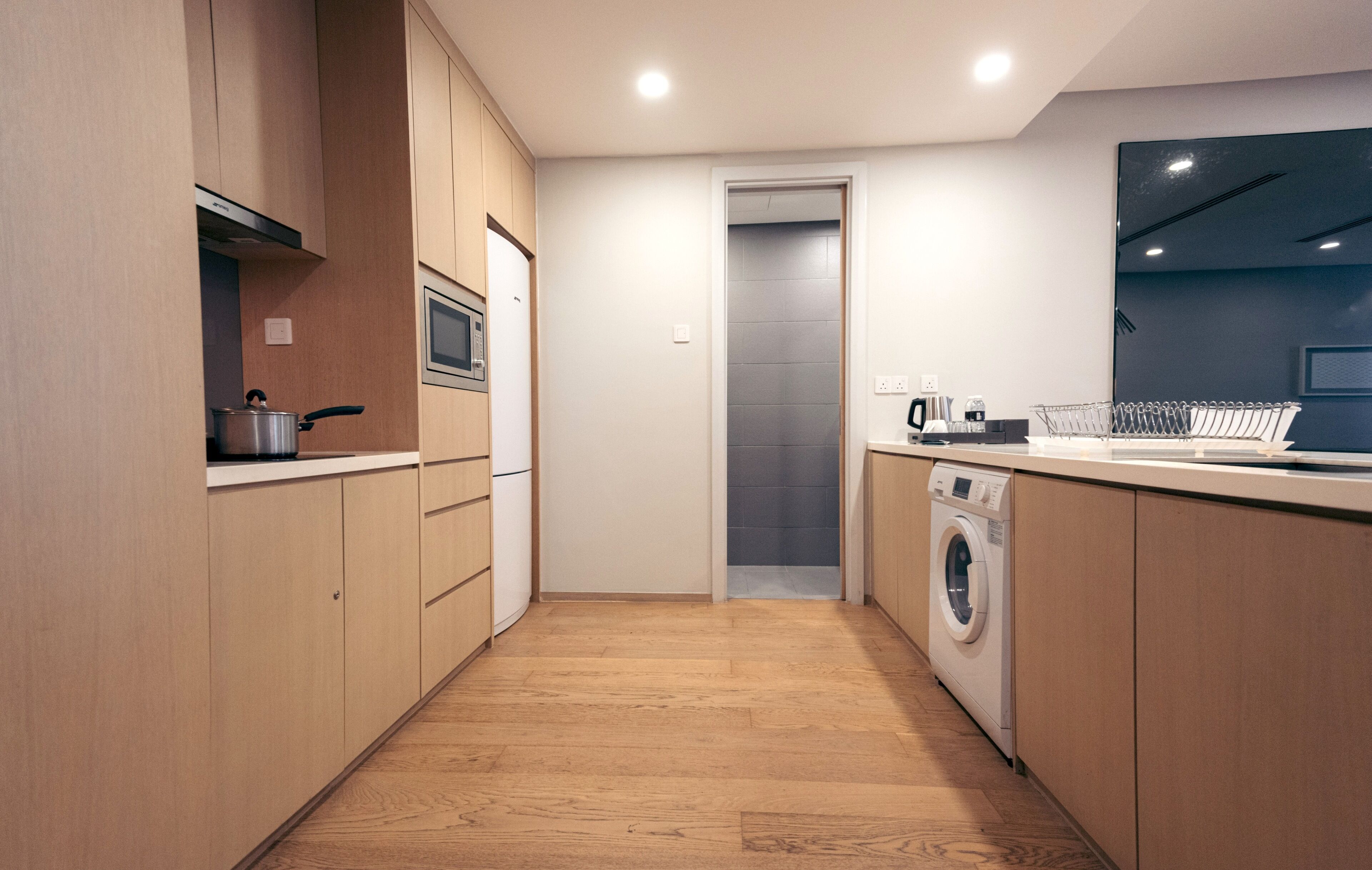 Una cocina moderna con armarios de madera, microondas, lavadora y lavaplatos.