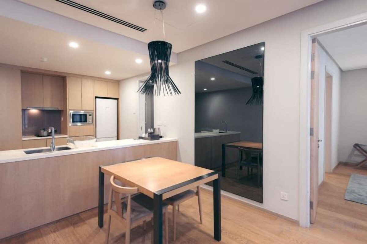A modern kitchen with a central island, a dining area with a table and chairs, and a view into an adjacent room.