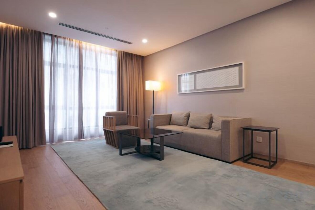 A modern living room with a sofa, armchairs, a coffee table, and a lamp.