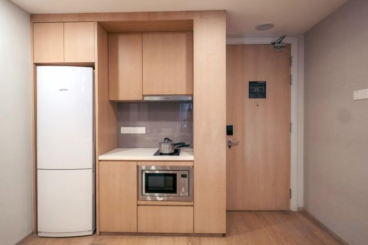 A compact kitchen with a built-in microwave, a small oven, and a refrigerator.