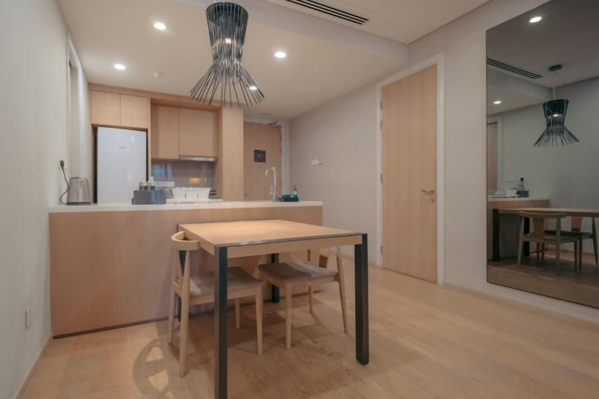 A modern kitchen with a central island, wooden flooring, and a dining area with a table and chairs.