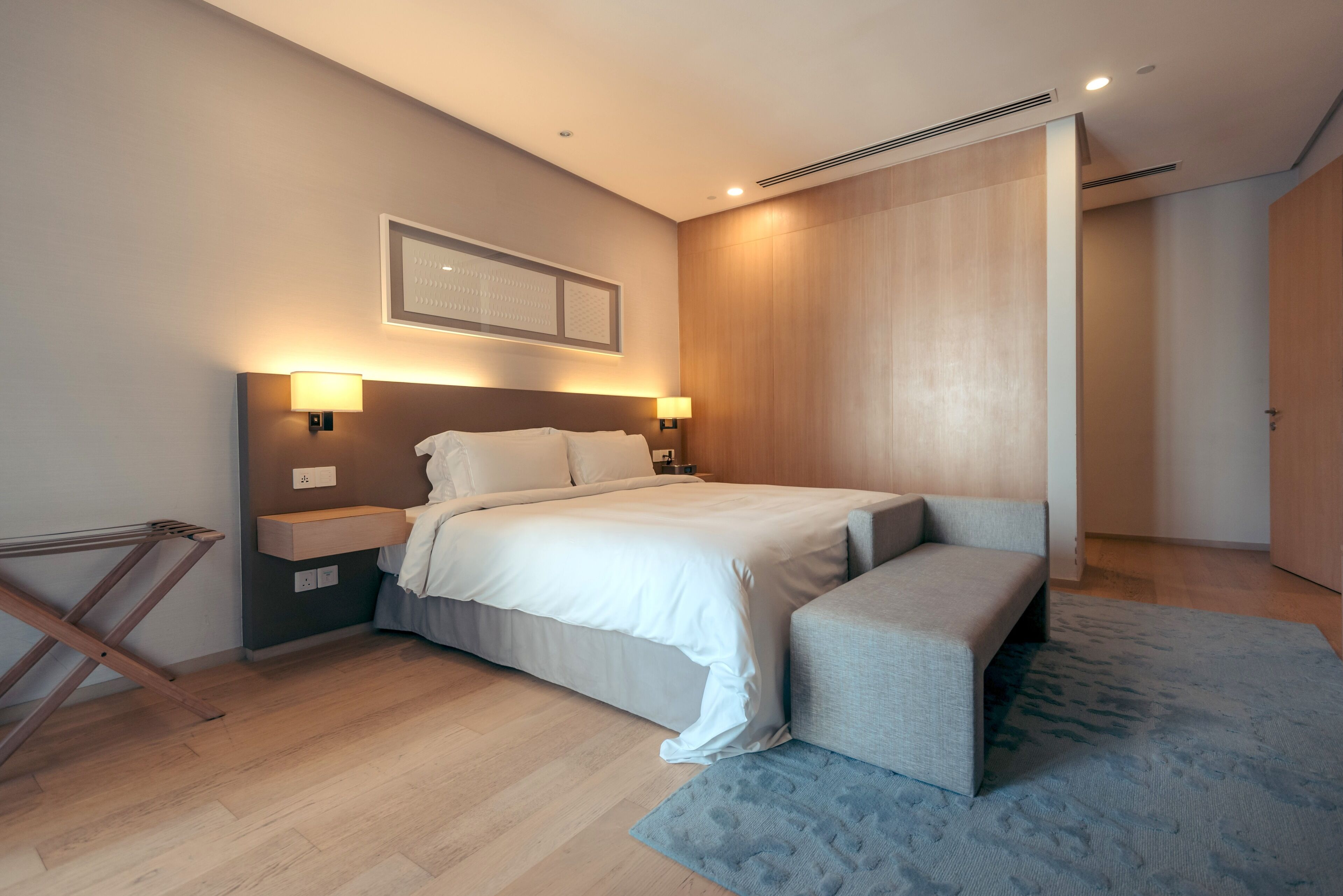 Un dormitorio moderno con una cama grande, mesitas de noche y un banco.
