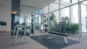 Een moderne sportschool met gewichthefapparatuur, banken en een groot raam met uitzicht op de stad.