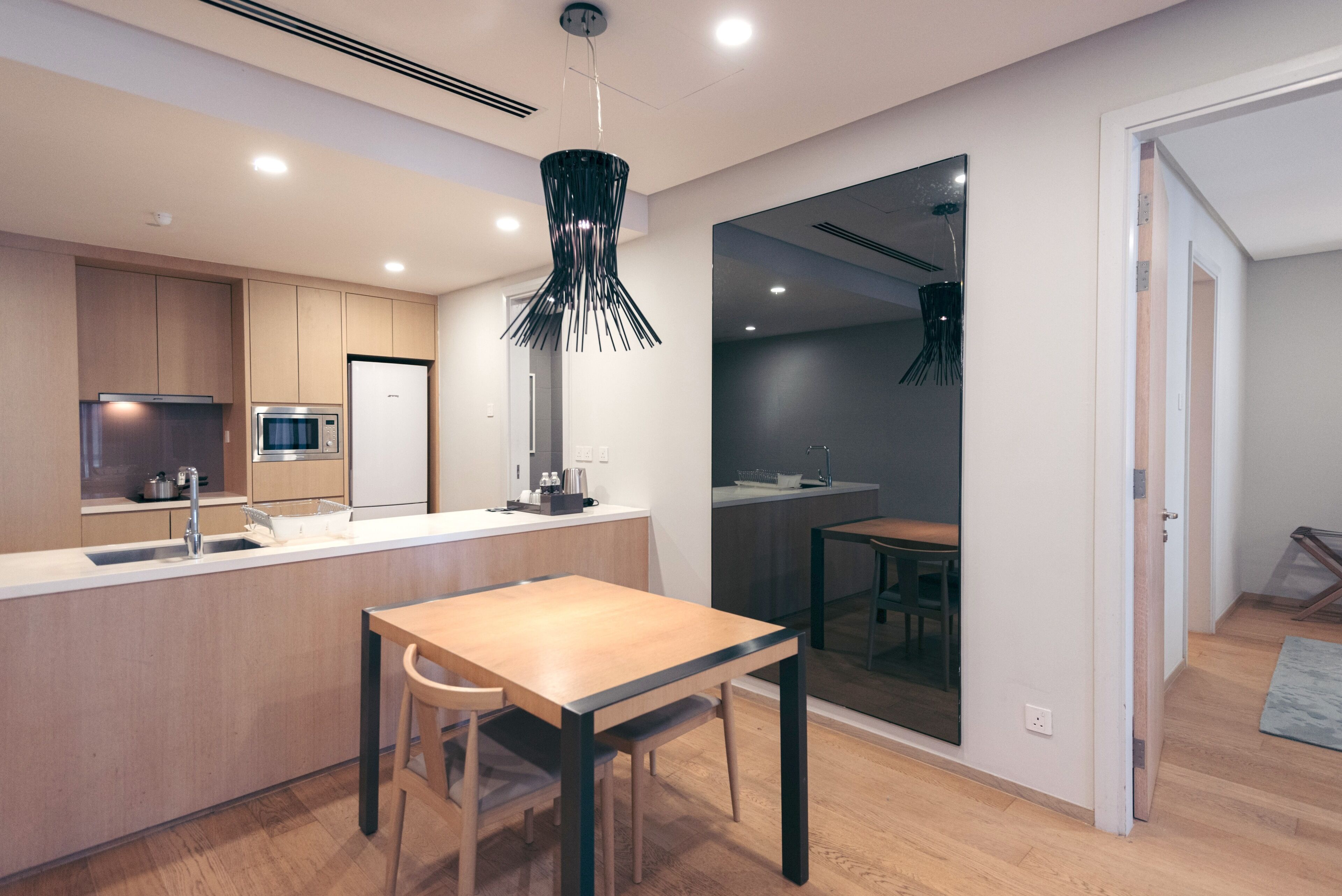 Una cocina moderna con una isla central, electrodomésticos de acero inoxidable y una lámpara colgante contemporánea.
