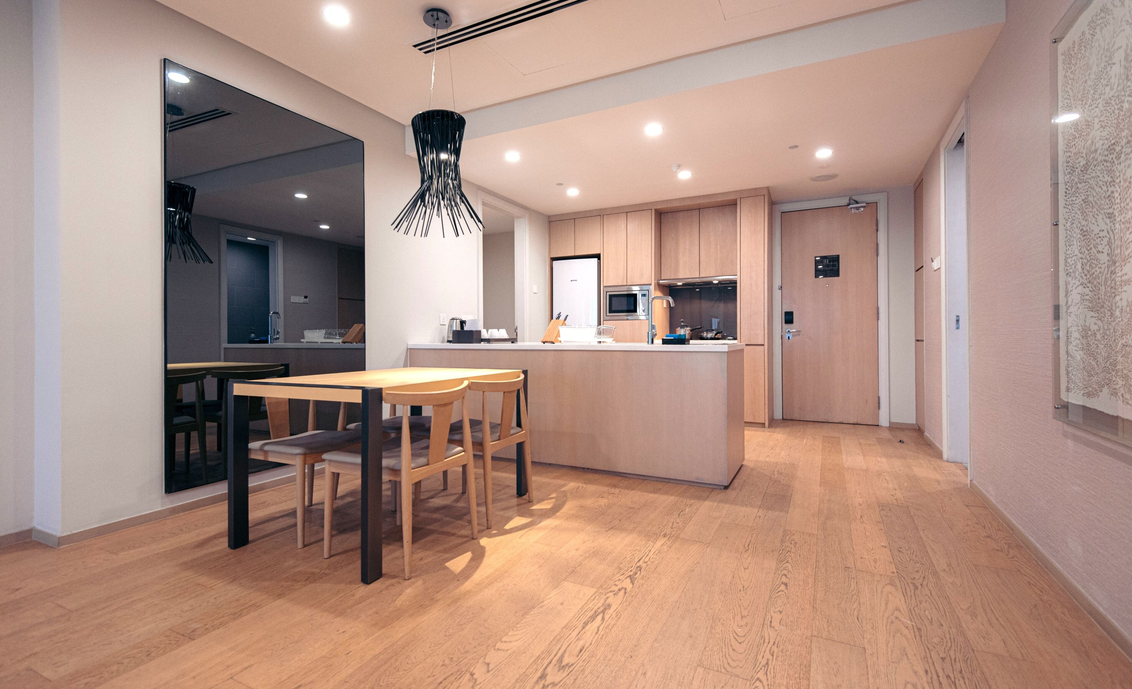 A modern kitchen with wooden cabinets, a central island, and a dining area with a wooden table and chairs.