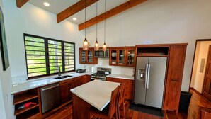 Une cuisine moderne avec des meubles en bois, un réfrigérateur en acier inoxydable et une grande fenêtre offrant une vue sur la verdure.