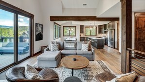 A spacious living area with a large sofa, a coffee table, and a view of the outdoors. - Hawk Ridge in the Highlands of Breck | Golf Course and Nordic Trails! (Breckenridge)