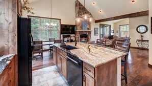 A spacious kitchen with a large island, wooden cabinets, and a stone fireplace.