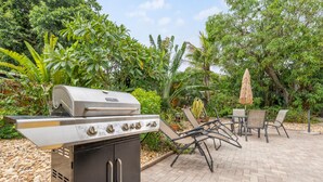 An outdoor grill area with a built-in oven, surrounded by a patio with chairs and a table. - Cozy 2BR Snowbird Home Near Wilton Manors (Fort Lauderdale)