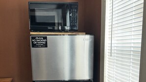 A stainless steel refrigerator with a microwave on top, a "No Smoking" sign, and a window with blinds. - Sunset Cabin-Adults Only Hot Tub Getaway (Hillsboro)
