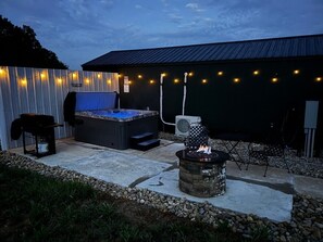 An outdoor patio area with a hot tub, a fire pit, and string lights. - Sunset Cabin-Adults Only Hot Tub Getaway (Hillsboro)