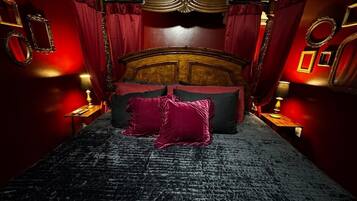 Une chambre avec un grand lit, des rideaux rouges et une tête de lit en bois.