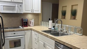 Una cocina moderna con armarios blancos, electrodomésticos de acero inoxidable y un salpicadero de azulejos.