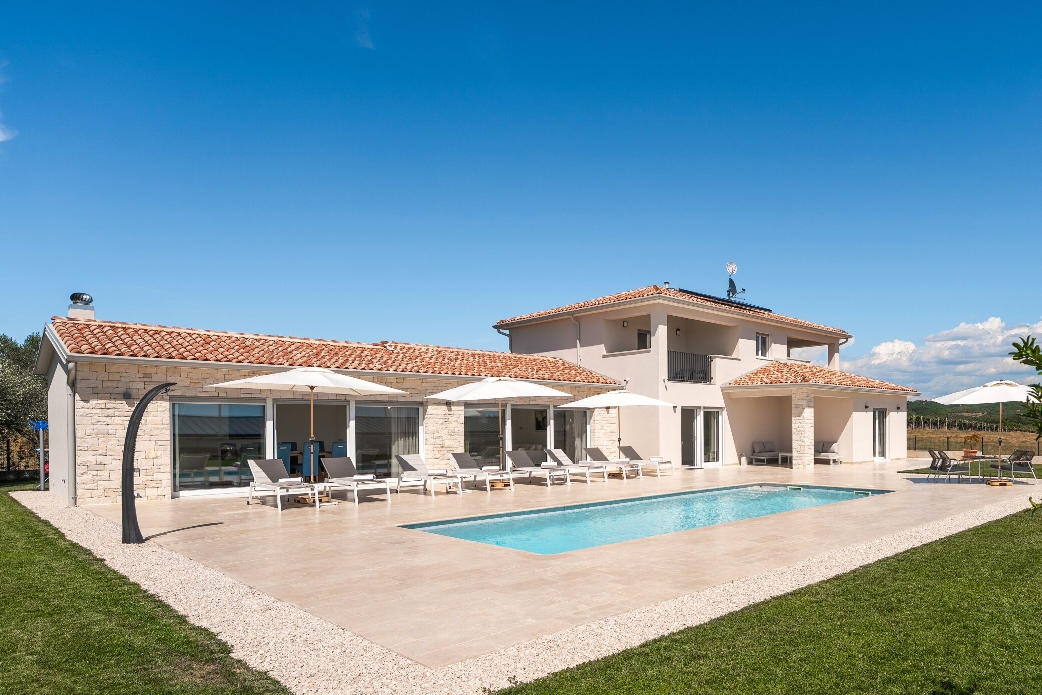 Une maison à deux étages dotée d’une piscine, d’un espace salon extérieur et d’un patio couvert.