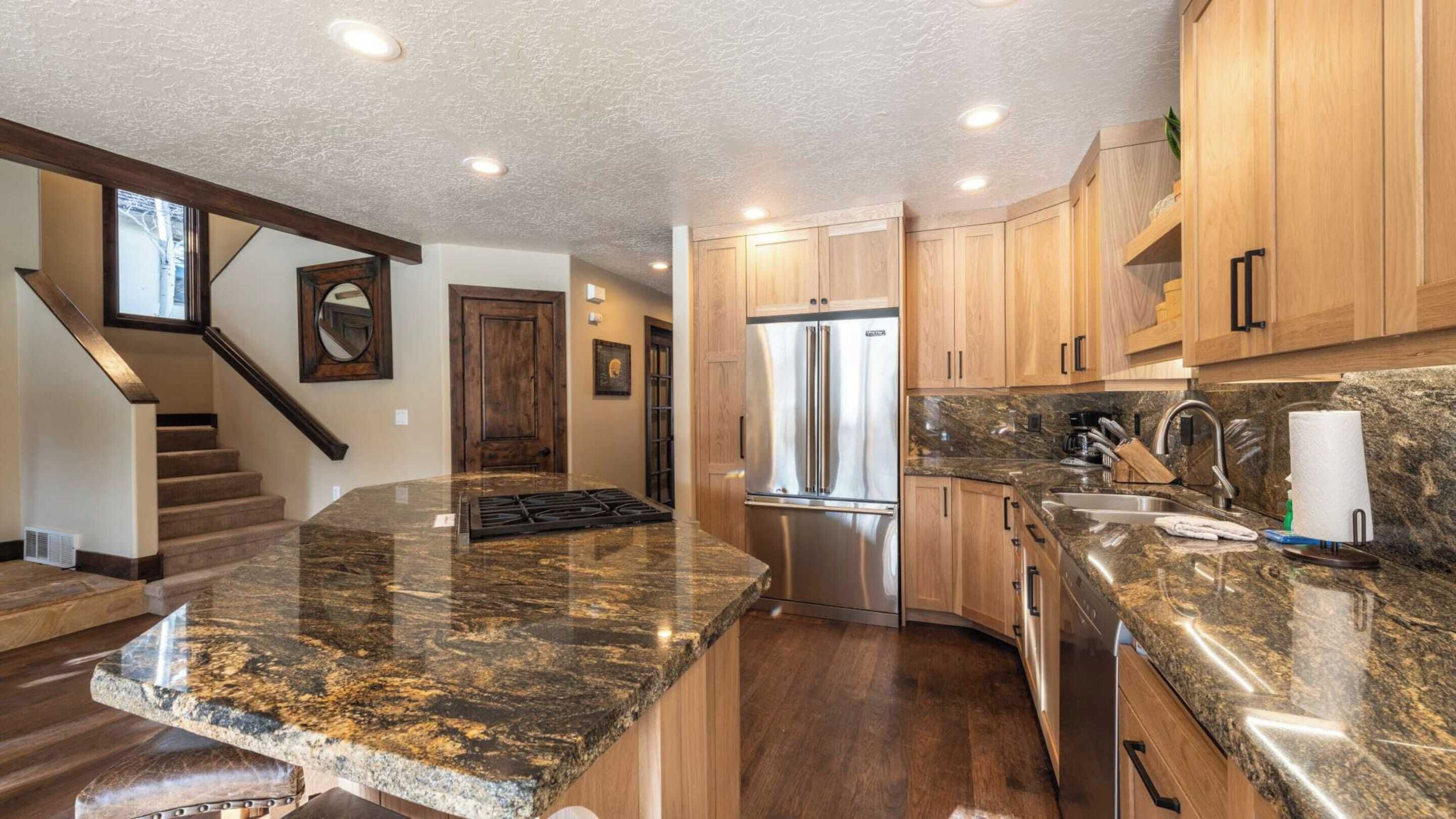 A modern kitchen with granite countertops, stainless steel appliances, and wooden cabinets.