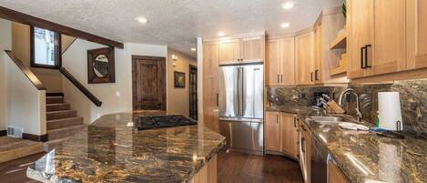 A modern kitchen with granite countertops, stainless steel appliances, and wooden cabinets.