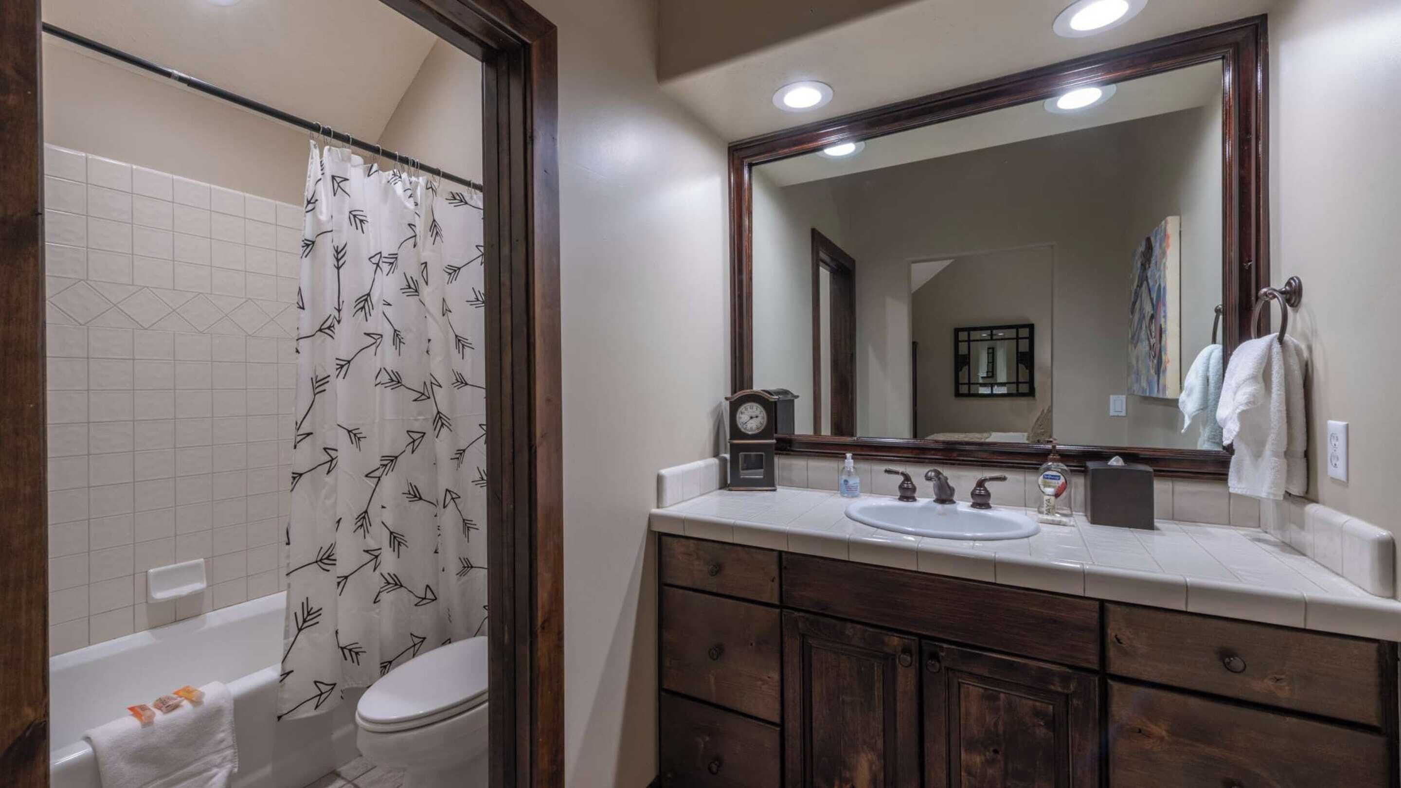 A bathroom with a shower, toilet, sink, and a large mirror.