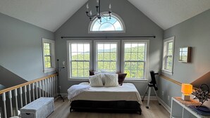 A bedroom with a sloped ceiling, large windows, a bed, a telescope, and a small stool. - Beautiful mountain views for a fun, relaxing getaway! (Seven Devils)