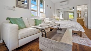 Une chambre moderne avec un canapé blanc, un cadre de lit en bois, une table de chevet et un grand miroir.