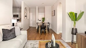 A modern living room with a sofa, coffee table, and dining area with chairs and a table.