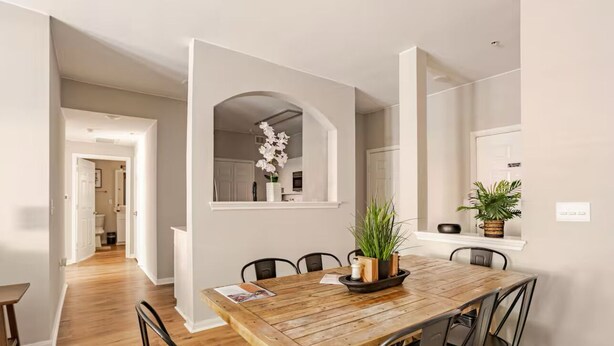 A dining area with a wooden table, black chairs, and a potted plant.