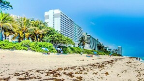 Una playa con un hotel al fondo.