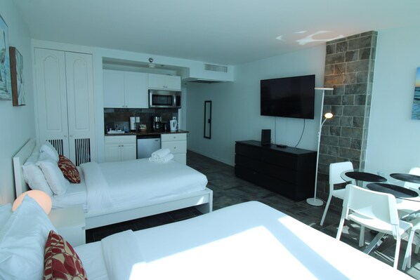 Une chambre d’hôtel moderne équipée d’un lit, d’un bureau, d’un téléviseur à écran plat et d’un coin repas avec des chaises et une table.