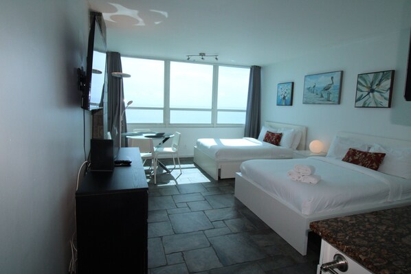 Una habitación de hotel con una cama, un escritorio, una silla, un televisor y obras de arte en la pared.