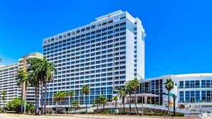 Un hotel moderno de varios pisos, con un edificio curvo y palmeras en primer plano.