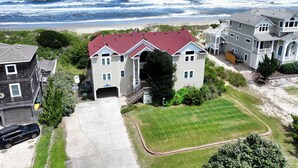 A coastal property with a large house featuring a red roof, a driveway, and a well-maintained lawn. - OCEANFRONT, priv pool & Hot Tub, Rec Room-WL1011, Sea Esta (Corolla)