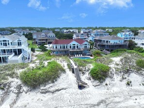 A beachfront property with multiple houses, a swimming pool, and a wooden walkway leading to the beach. - OCEANFRONT, priv pool & Hot Tub, Rec Room-WL1011, Sea Esta (Corolla)