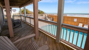 Une terrasse en bois avec une piscine, des rampes en bois et une vue sur l’océan.